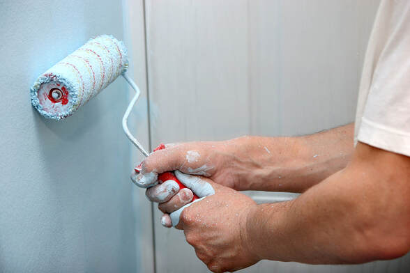 In Norwalk, CT, a house painter uses a roller to paint a wall in motion.