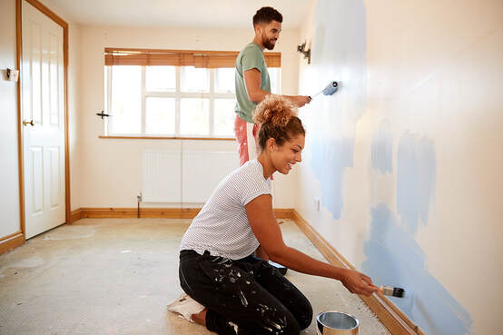 Couple decorating a new home in Norwalk, CT, painting walls together.