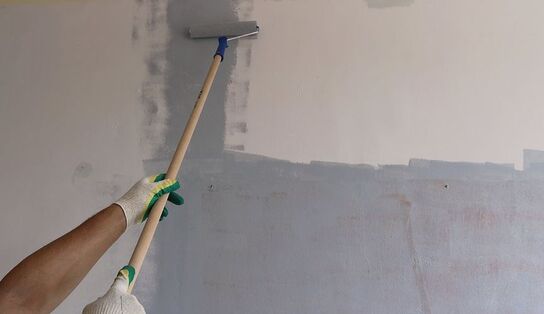 The painter in Norwalk, CT, uses a long-handled roller to reach hard-to-reach places when painting a wall.
