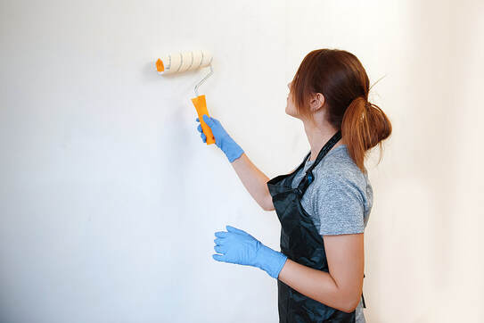 A young woman paints walls in a new house in Norwalk, CT, with a roller.