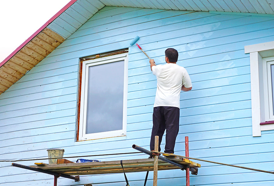 A house painter paints the trim and shutters of a home in Norwalk, CT.